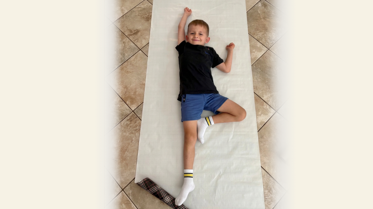 young boy laying on piece of paper for superhero silhouette craft