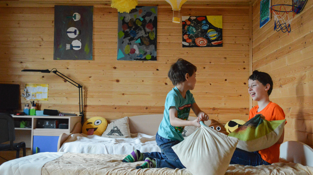 two young kids having a pillow fight in bed