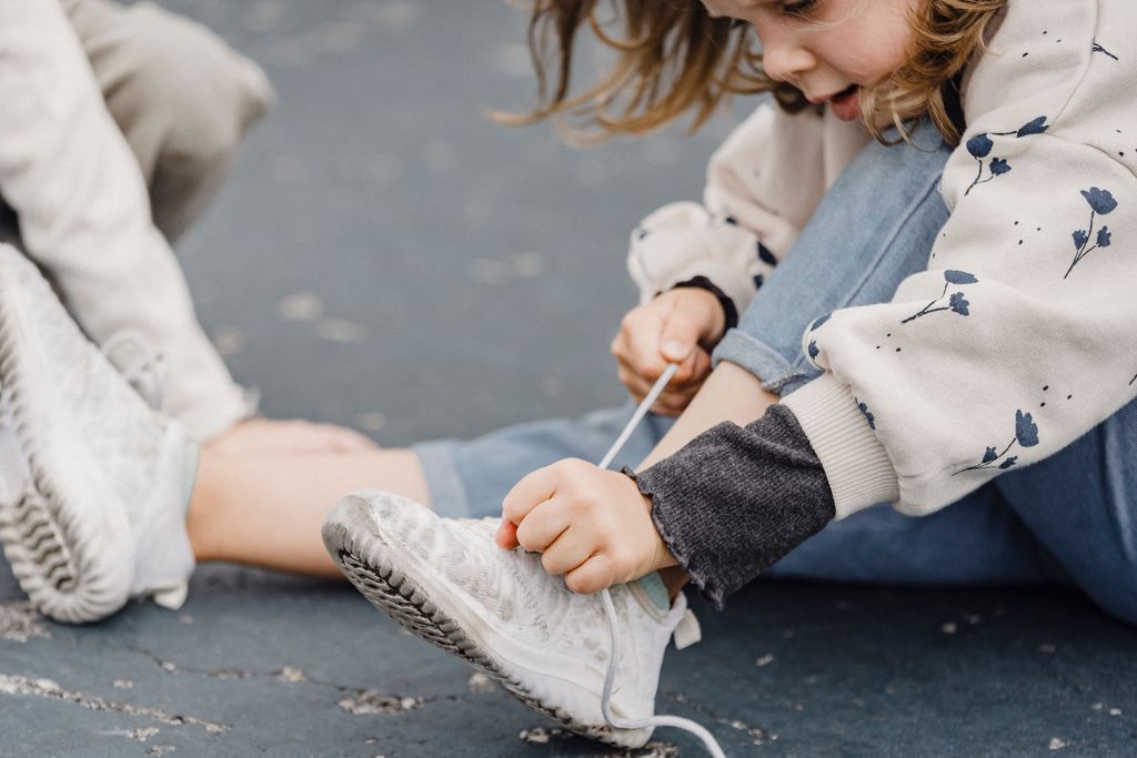 child tying her shoes.